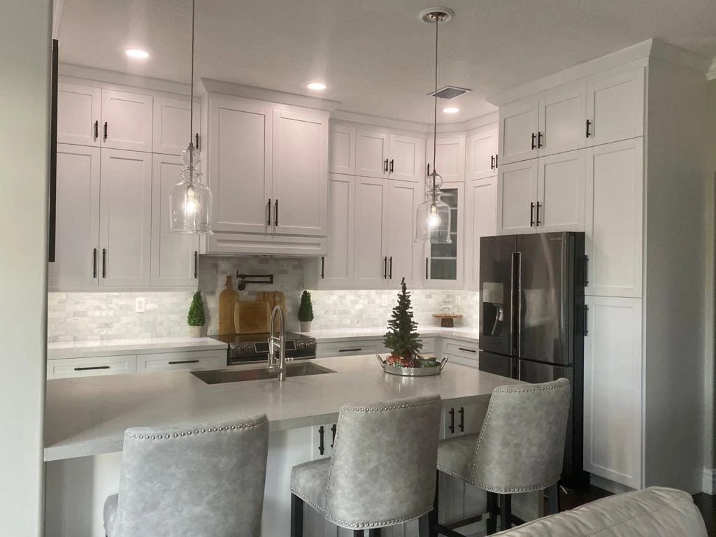 White kitchen with pendant lights above an island and upholstered seating